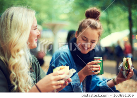 Time for some refreshments. Two young women drinking and having a snack at an outdoor festival. Time for some refreshments. Two young women drinking and having a snack at an outdoor festival. 103691109