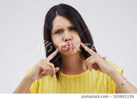 Am I making you laugh yet. Studio shot of a young woman making a funny face against a gray background. 103691159
