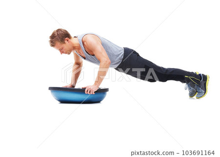Building his upper body strength. A young man working his upper body using a bosu-ball. 103691164