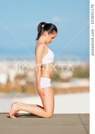 Woman, healthy body and stretching on roof top in fitness for exercise, zen or workout outdoors. Female yogi in warm up stretch for yoga, wellness or training in balanced lifestyle in an urban town 103691176