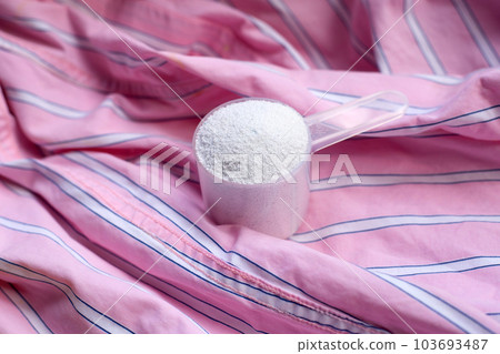 Detergent powder in measuring spoon on cloth before washing. Laundry concept. 103693487