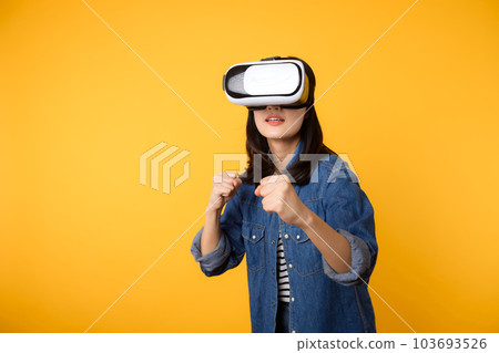 Young asian woman get experienced wearing virtual reality headset game entertainment isolated on yellow background. Winner of cyber future video game concept. 103693526
