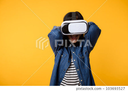 Young asian woman get experienced wearing virtual reality headset game entertainment isolated on yellow background. Winner of cyber future video game concept. 103693527