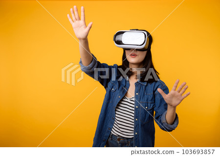 Young asian woman happy success wearing virtual reality headset game entertainment isolated on yellow background. Winner of cyber future video game concept. 103693857