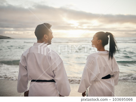 Keep calm and practice your kata. Rearview shot of two young martial artists practicing karate on the beach. 103695066
