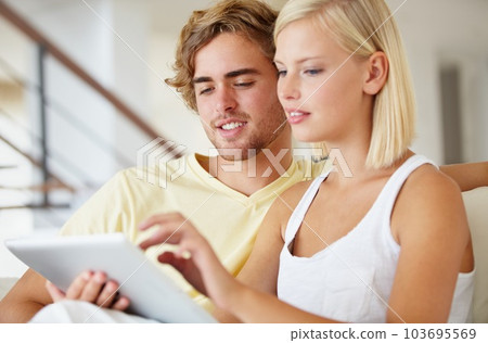 Navigation is easy on a tablet. A pretty young woman navigating her tablet while her boyfriend watches. 103695569