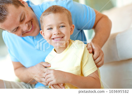Happy afternoons spent with dad. Young boy smiling widely while his father tickles him. Happy afternoons spent with dad. Young boy smiling widely while his father tickles him. 103695582