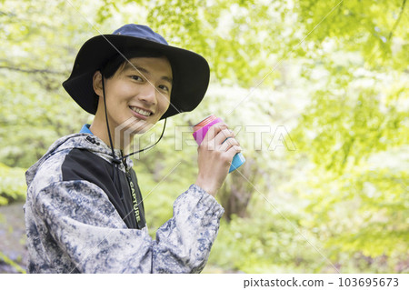 A young man drinking a drink in the forest Outdoor image A young man drinking a drink in the forest Outdoor image 103695673