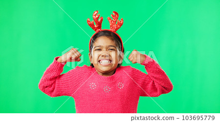 Child portrait, christmas and antlers on green screen flexing strong muscles or arms for motivation. Smile on face of a girl kid on a studio background with reindeer headband for holiday celebration Child portrait, christmas and antlers on green screen flexing strong muscles or arms for motivation. Smile on face of a girl kid on a studio background with reindeer headband for holiday celebration 103695779