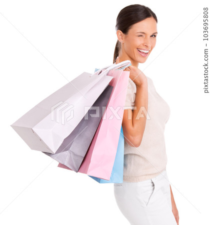 Shes knows where to get the best deals. An attractive young woman carrying shopping bags over her shoulder. 103695808