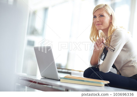 Thinking, young businesswoman with laptop and glasses at desk in office at work. Corporate, planning or idea and female entrepreneur with notebooks on table at modern workplace with computer 103696336