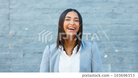 Cheerful woman laughing and giggling about something funny while standing outside against a grey wall with copy space. Happy businesswoman having fun and expressing positivity and a playful attitude 103696353