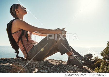 Shes truly living the adventure. a young woman taking a break while out on a hike through the mountains. 103696372