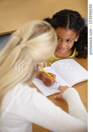 Woman helping girl, education and writing in notebook with pencil, teaching and learning for growth and development. People in classroom to learn, academic study with teacher and student at school Woman helping girl, education and writing in notebook with pencil, teaching and learning for growth and development. People in classroom to learn, academic study with teacher and student at school 103696688