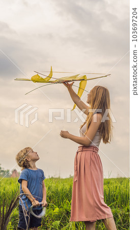 Mom and son launch a kite in a rice field in Ubud, Bali Island, Indonesia VERTICAL FORMAT for Instagram mobile story or stories size. Mobile wallpaper 103697204