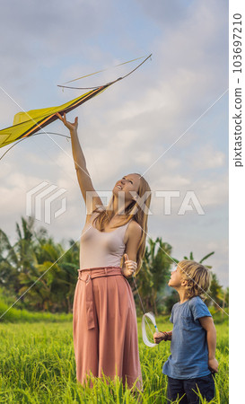 Mom and son launch a kite in a rice field in Ubud, Bali Island, Indonesia VERTICAL FORMAT for Instagram mobile story or stories size. Mobile wallpaper 103697210