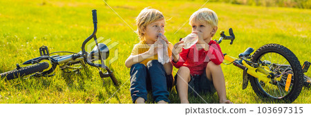 Two little boys drink water in the park after riding a bike BANNER, LONG FORMAT 103697315