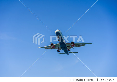 A white airplane flying in a clear pale blue sky A white airplane flying in a clear pale blue sky 103697597