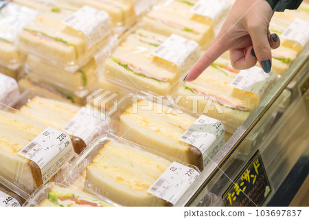 Young woman's hand pointing to a sandwich in the supermarket counter Young woman's hand pointing to a sandwich in the supermarket counter 103697837