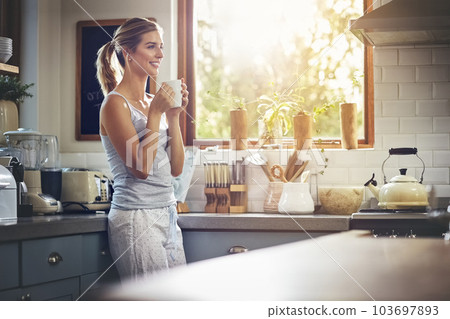 Coffee helps me to get my feet out the door. a young woman having her morning coffee. 103697893