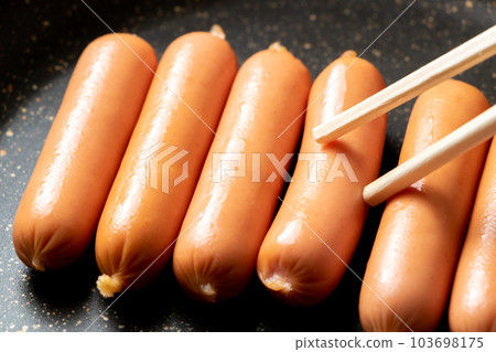 在煎鍋中烘烤維納香腸。 在煎鍋中烘烤維納香腸。 103698175