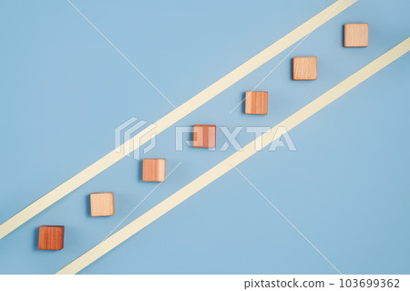 blank wooden cubes in a diagonal line shades ranging from dark to light beige on blue background. Minimalistic abstract concept representation of progress and diversity. Top view flat lay copy space 103699362