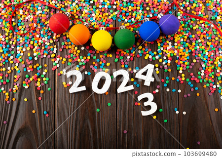 White numbers 2024 and color sugar sprinkles on wooden table with color balls garland White numbers 2024 and color sugar sprinkles on wooden table with color balls garland 103699480