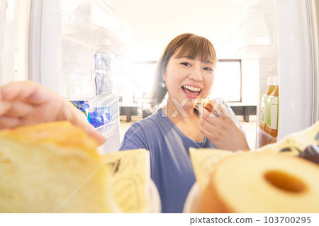 Young woman trying to open the refrigerator and take a cake Young woman trying to open the refrigerator and take a cake 103700295
