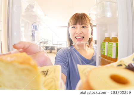 Young woman trying to open the refrigerator and take a cake Young woman trying to open the refrigerator and take a cake 103700299