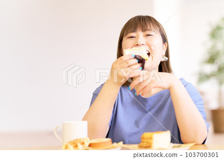 A young woman happily eating a cake A young woman happily eating a cake 103700301