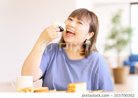 一個快樂地吃蛋糕的年輕女人 103700302