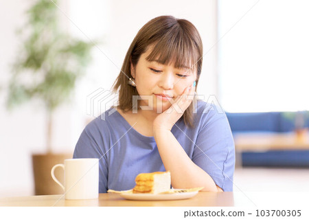 Young woman looking at the cake on the table 103700305