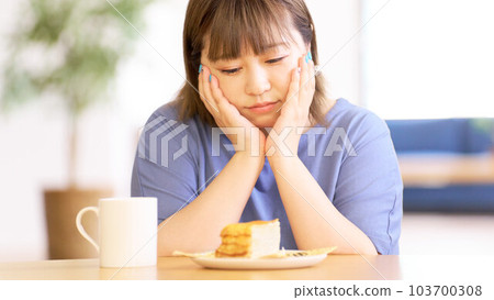 Young woman looking at the cake on the table 103700308