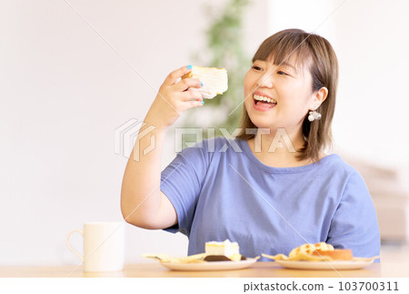 A young woman staring at the cake in her hand 103700311