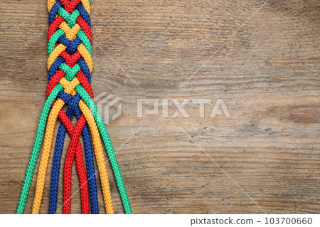 Top view of braided colorful ropes on wooden background, space for text. Unity concept Top view of braided colorful ropes on wooden background, space for text. Unity concept 103700660