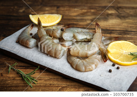 Fresh raw shrimps with lemon and rosemary on wooden table, closeup 103700735