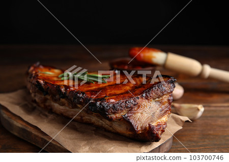 Tasty grilled ribs with rosemary on wooden table, closeup 103700746