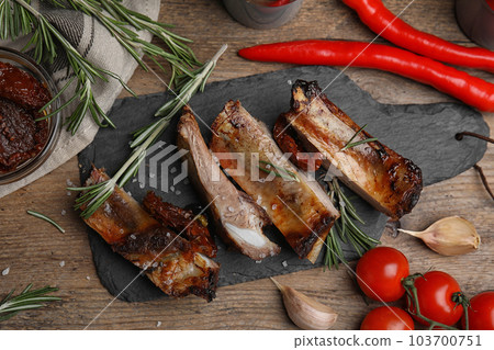 Tasty grilled ribs with rosemary on wooden table, flat lay Tasty grilled ribs with rosemary on wooden table, flat lay 103700751