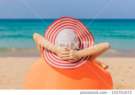 Summer lifestyle portrait of pretty girl sitting on the orange inflatable sofa on the beach of tropical island. Relaxing and enjoying life on air bed Summer lifestyle portrait of pretty girl sitting on the orange inflatable sofa on the beach of tropical island. Relaxing and enjoying life on air bed 103701072