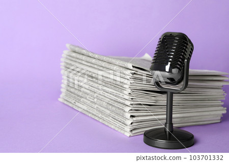 Newspapers and vintage microphone on light violet background. Journalist's work 103701332