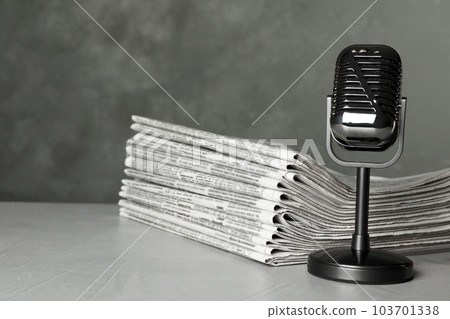 Newspapers and vintage microphone on light grey stone table. Journalist's work 103701338