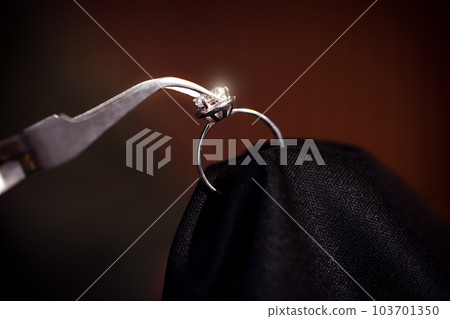 Working with beautiful ring on dark background, closeup. Jeweler's workshop Working with beautiful ring on dark background, closeup. Jeweler's workshop 103701350