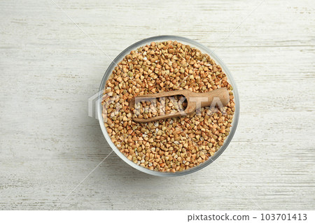 Uncooked green buckwheat grains in bowl on white wooden table, top view Uncooked green buckwheat grains in bowl on white wooden table, top view 103701413