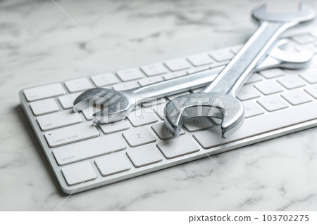 Keyboard and spanners on white marble table, closeup. Concept of technical support 103702275