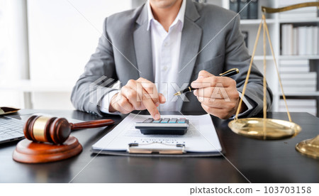 Lawyer or accounting department writes a note and uses a calculator to calculate expenses - income. at office lawyer. 103703158