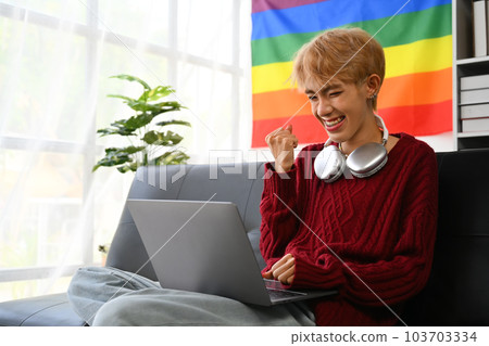 Excited young Asian gay man looking at laptop screen, making winner yes gesture, celebrating success 103703334