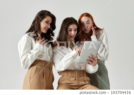 Portrait of beautiful, elegant, young women in stylish clothes, blouse and pants posing against light studio background Portrait of beautiful, elegant, young women in stylish clothes, blouse and pants posing against light studio background 103704416