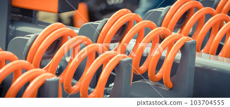 Big and hard orange steel spring as part and detail of industrial or agricultural machine Big and hard orange steel spring as part and detail of industrial or agricultural machine 103704555
