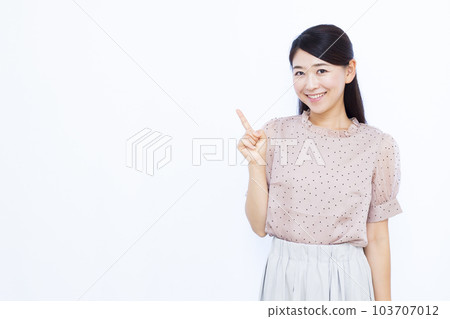 A woman in her thirties who raises her index finger in front of a white background 103707012