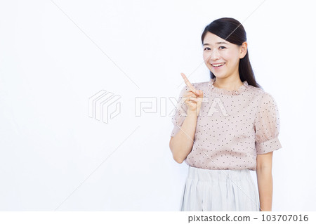A woman in her thirties who raises her index finger in front of a white background 103707016